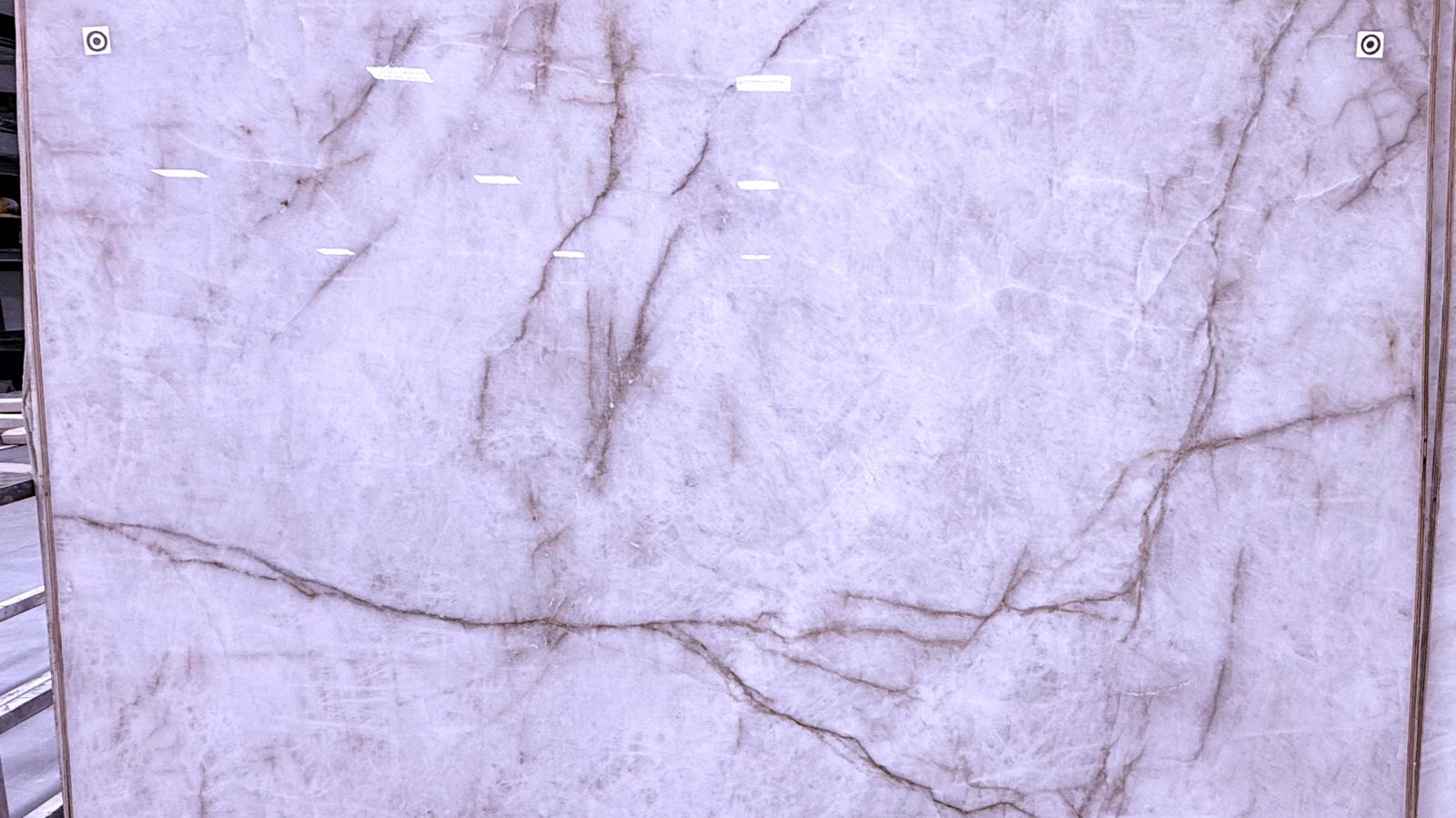 Close-up of a light Brazilian quartzite slab with soft veining, tagged at the Peak Stoneworkz warehouse.